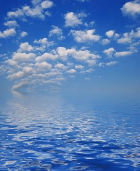 Blue sky with white clouds reflected in the water surface with small waves