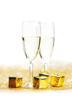 Champagne in glasses and gift box on golden background