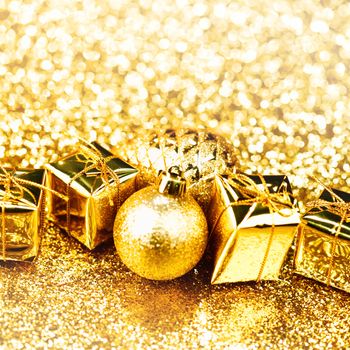 Golden Christmas ball and gifts on abstract glitter background