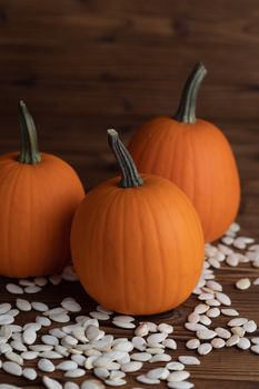 Fresh orange pumpkins and pimpkin seeds close-up on wooden background