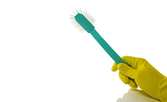 hand with yellow household glove holding a green washing-up brush on a white background