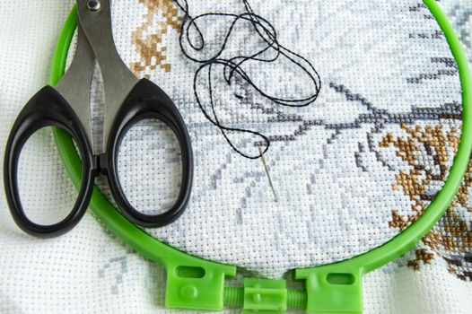 Flat lay canvas with a beautiful pattern of bright sewing threads, scissors and a needle for embroidery close-up.