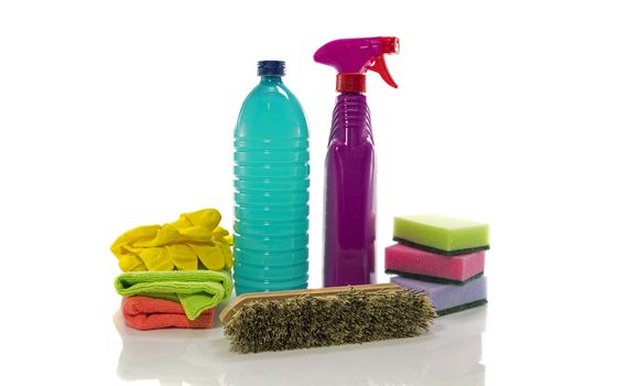 Cleaning supplies on white background including several spray bottles of chemicals, rubber gloves and sponges