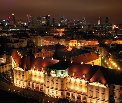 Aerial view of the royal castle in the old town at night, Warsaw, Poland. In the background are visible modern skyscrapers, downtown
