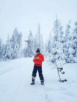 Snowboarder controls the drone during a break in skating. Beautiful winter landscape on the background