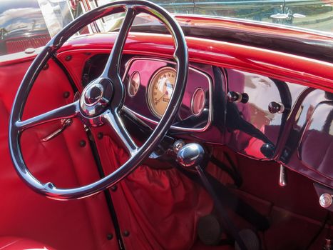 View of the red interior of a classic antique car, with steering wheel and dashboard, very beautiful.