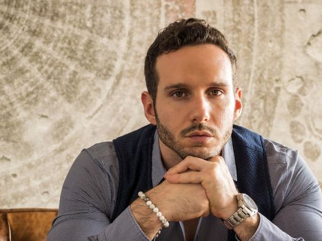 Attractive young man indoors wearing a shirt and beaded bracelets