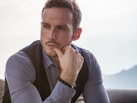 Attractive young man indoors wearing a shirt and beaded bracelets