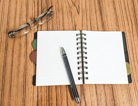 Desk with open notebook with blank pages, eye glasses and a pen. Top view with copy space. Business still life concept with office stuff on table. Education, working, planning concept. Top View.