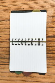 Blank empty notepad on a wood table. Top view image of open pocket planner notebook with empty pages ready for adding text or mockup.