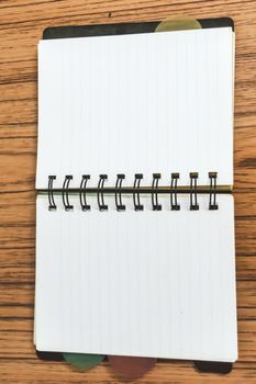 Blank empty notepad on a wood table. Top view image of open pocket planner notebook with empty pages ready for adding text or mockup.