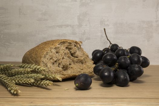 A wheat bread and shock of wheat with red grapes as easter lst supper background