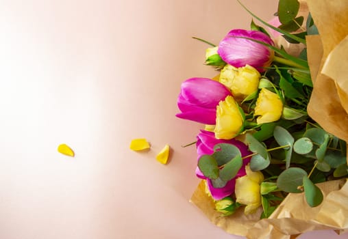 Flat lay creative layout is made with red and yellow flowers on pink background. The concept of spring.