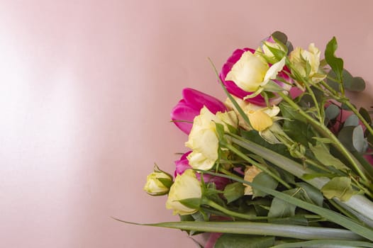 Flat lay flower arrangement with roses and tulips on a pink background top view.