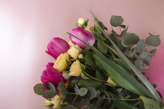 Flat lay flower arrangement with roses and tulips on a pink background top view.