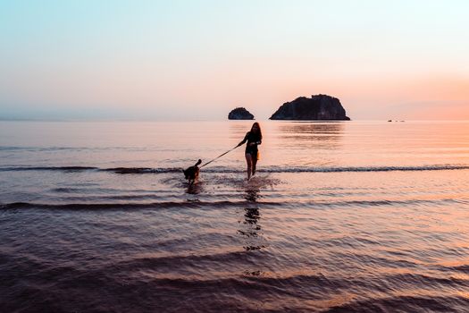 Woman and dog on beach at sunrise