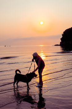 Senior Woman and dog on beach at sunrise