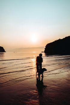 Senior Woman and dog on beach at sunrise