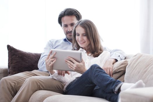 Cheerful couple using digital tablet at home