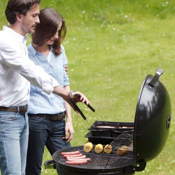 Happy couple cooking food on barbecue