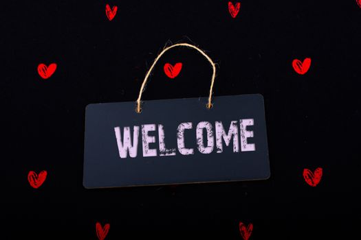 Welcome wording on black notice board  with red hearts around