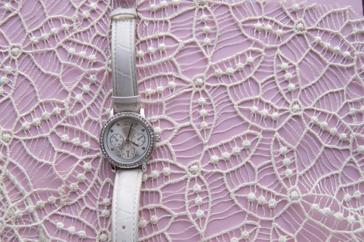 Stylized photo for business women, social networks, women's posts, modern women's wristwatch on a noble lace and pink background. Empty space