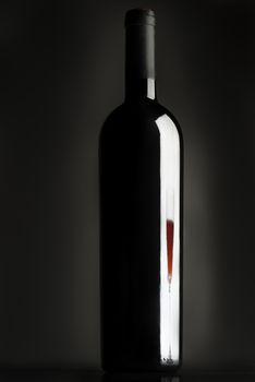 Bottle of wine, reflection of wine glass, red wine, black background