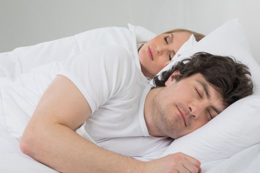 Mid age couple sleeping in bed at home in bedroom