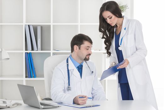 Young assistant and doctor checking medical records and documents