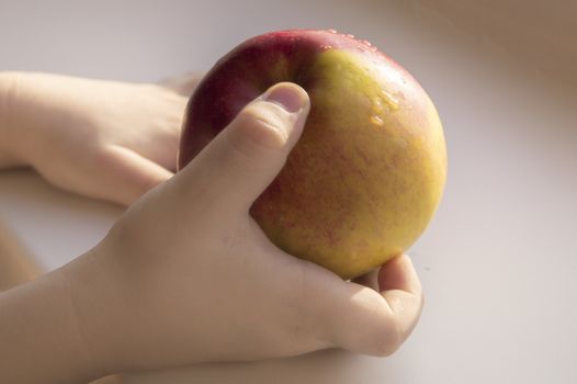 The child holds a ripe Apple in his hand, close-up. sunlight, concept of healthy nutrition for children.