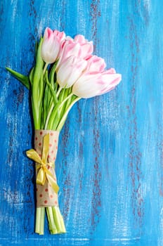 Bouquet of pink tulips on a blue wooden background, space for the inscription.