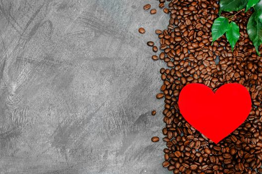 Red cardboard heart on a pile of coffee beans on a vintage background.