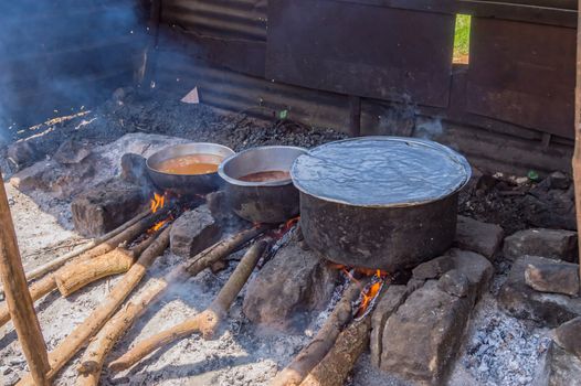 Three large saucepans resting on log fires in a small stall of a restaurant near the city of Thika in central Kenya