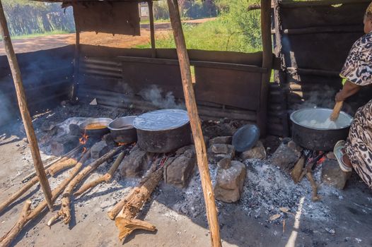 Four large saucepans resting on log fires in a small stall of a restaurant near the city of Thika in central Kenya