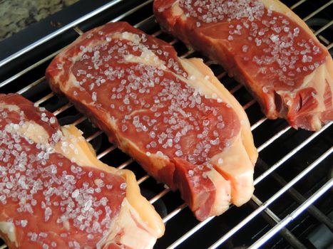 Raw beef steak with salt on the grill