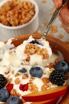 Close up portion of muesli granola breakfast with yogurt, fruits and berries, elevated top view, directly above