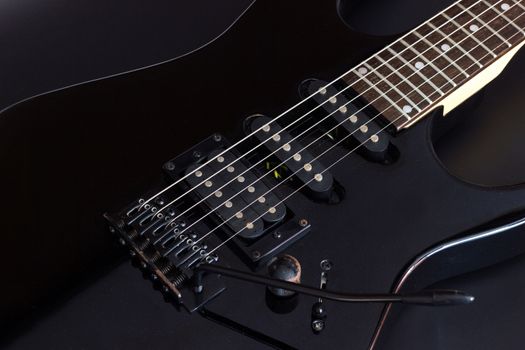 Black electric guitar on dark background.