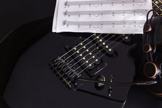 Music note, Headphone and electric guitar on black background.