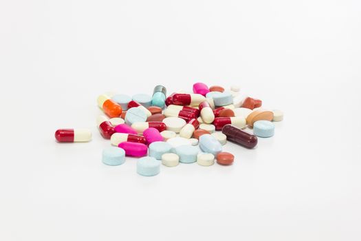 Multicolor antibiotics tablets and capsules on white background.