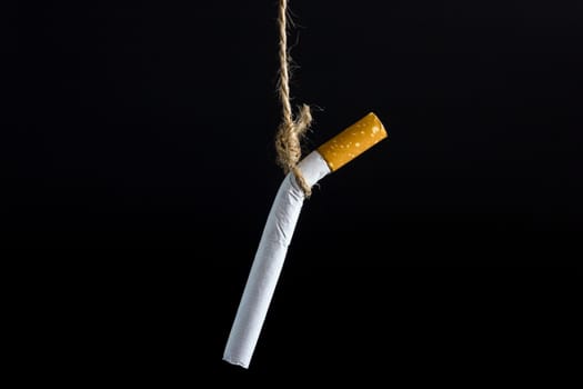 Anti Tobacco, Cigarette was hanged with a rope on dark background.