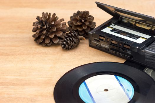 Old gramophone record, Old portable taps player, Cassette, Dry pine flower on wood background.