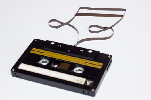 Music note sign. Cassette tape on white background. Film shaping music note.