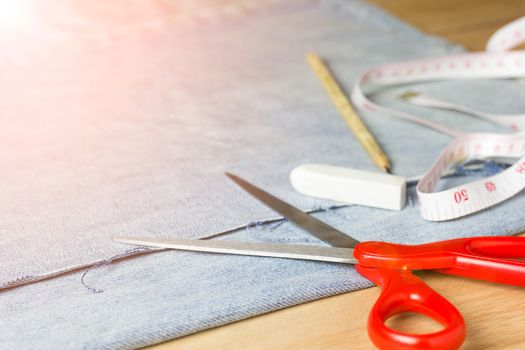 Equipment for jeans fabric cutting on brown wood background.