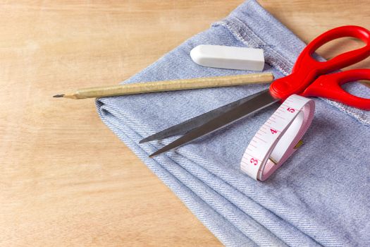 Equipment for jeans fabric cutting on brown wood background.