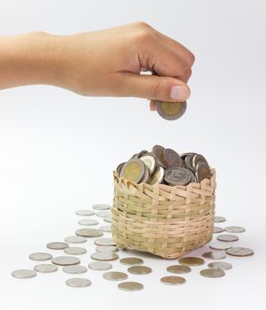 Hand holding coin over a bamboo basket. Concept financial or business. Keep saving money for good thing in the future.