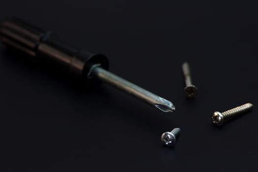 Screwdrivers and nut screws placed side. Low key Tools on darkness background.