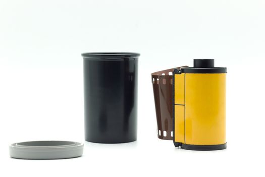 Black film bottle with gray bottle cap and yellow roll film on a white background.