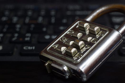 Old Password Key Lock placed on the black notebook keyboard in darkness. The concept of password security in computer systems.