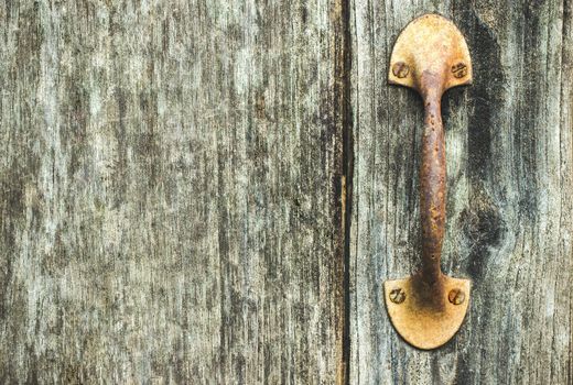 The vintage door handle rust on the wooden door of the old house.