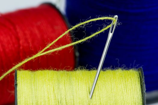 Close up Thread roller Blue, Red, Yellow and Sewing Needles in white background.Use to repair the tear of clothing.